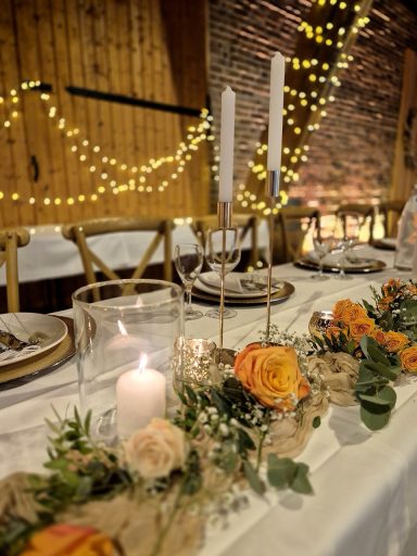 Elegant gedeckte Tafel mit Kerzen, Blumen und Lichtern in gemütlicher Atmosphäre.