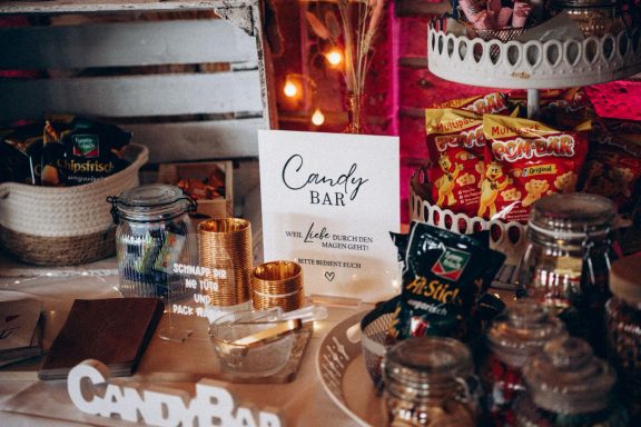 Ein dekorierter Candy Bar mit Süßigkeiten, Gläsern und einem Schild mit "Candy Bar".